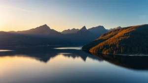 Aerial drone shot of Lake George at golden hour, mountain ridges reflecting in calm water, dense forest surrounding the shoreline, professional cinematography style, no text or watermarks, vibrant natural colors